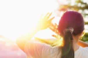 Woman blocking sun because of light sensitivity. 